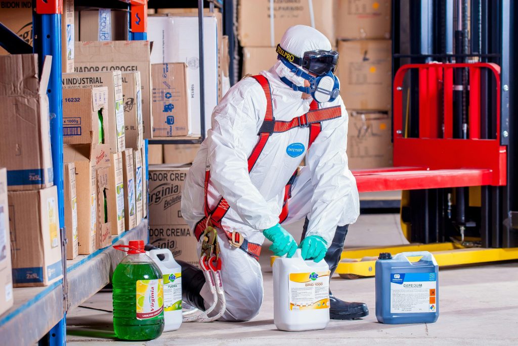 pexels-photo-209230-209230 Industrial worker in protective gear handling chemicals in a warehouse environment.